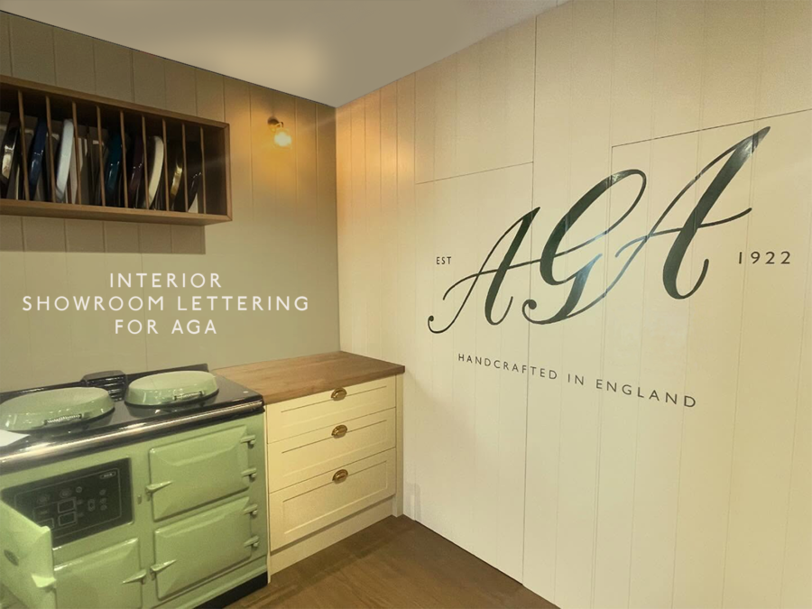 Pastel green vintage AGA stove in a cream kitchen showroom with wooden cabinets and wall mural.