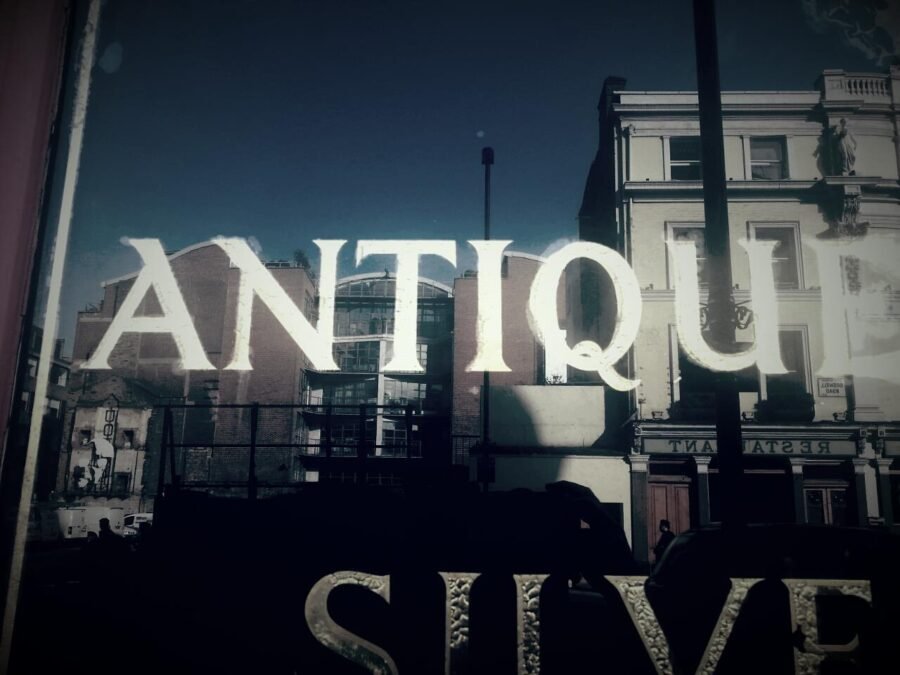 Storefront window with large white sign reading ANTIQU(E) in reverse glass gilding
