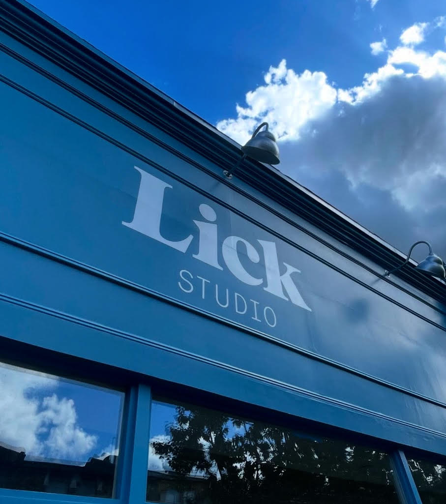 London Sign Writers | NGS Sign lettering & writing. NGS London Sign Writers'Lick Studio' sign on the facade under a bright sky with clouds.