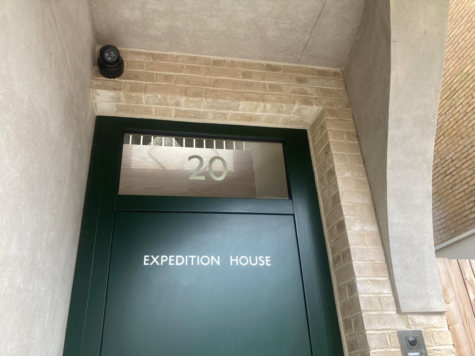 Green entry door at Expedition House, street number 20 on a metal panel above the door.